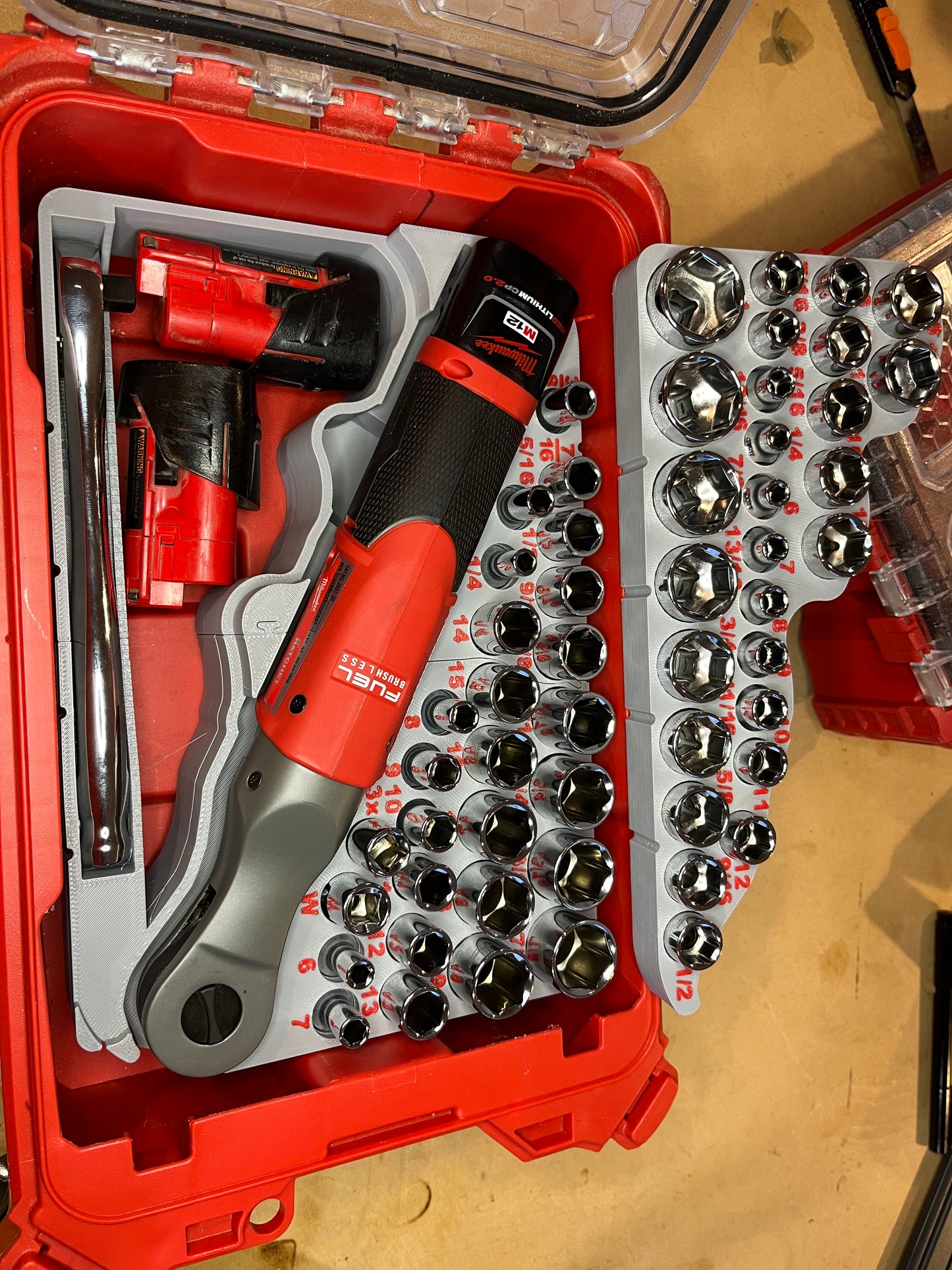 Removable shallow socket tray has room for 2 small M12 batteries and manual ratchet underneath. With tray removed, there’s room for 2 large batteries.